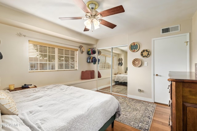 bedroom with multiple windows, a closet, ceiling fan, and light hardwood / wood-style flooring