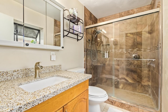 bathroom featuring vanity, an enclosed shower, and toilet