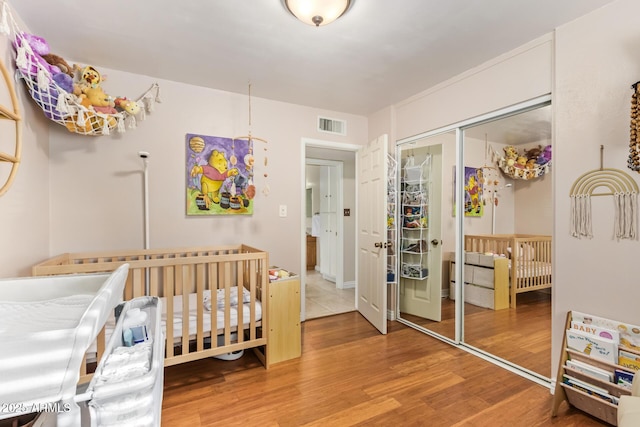 bedroom featuring hardwood / wood-style flooring, a nursery area, and a closet