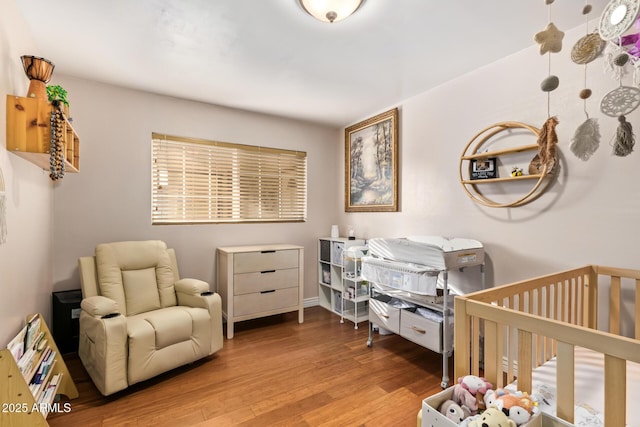 bedroom with a nursery area and light hardwood / wood-style flooring