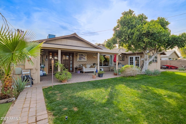 rear view of property with a patio and a lawn