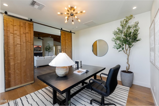 office area featuring a barn door, hardwood / wood-style floors, and a chandelier