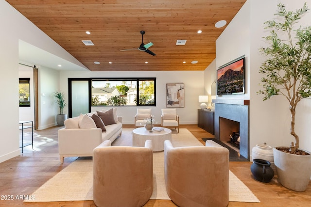 living room with a barn door, wooden ceiling, high vaulted ceiling, and light hardwood / wood-style flooring