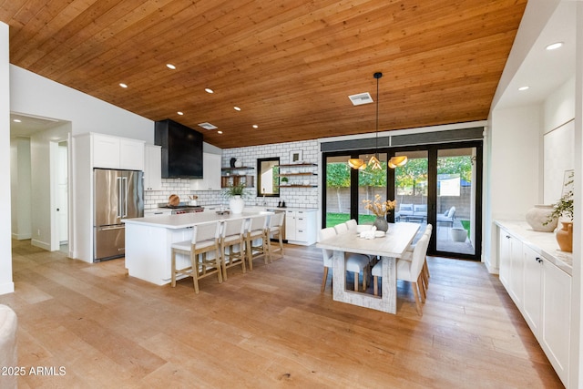 kitchen with high end fridge, a kitchen island, pendant lighting, light hardwood / wood-style floors, and white cabinets