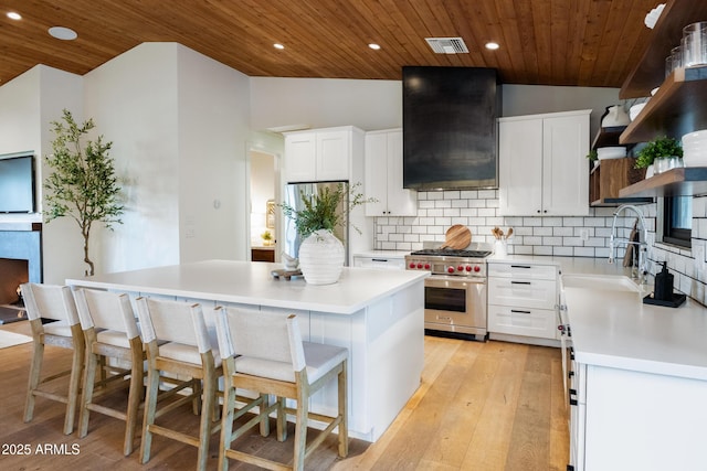 kitchen featuring a kitchen island, ventilation hood, white cabinets, and appliances with stainless steel finishes