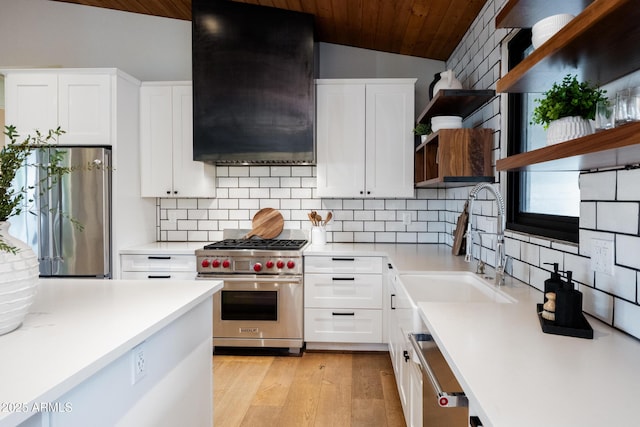 kitchen with lofted ceiling, sink, extractor fan, stainless steel appliances, and white cabinets