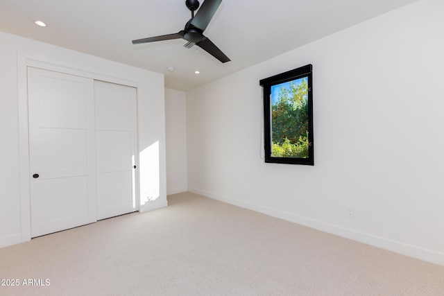 unfurnished bedroom with light carpet, a closet, and ceiling fan