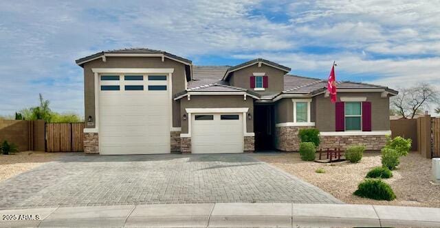 3907 S 75th Dr, Phoenix, AZ 85043 - view of front of house with driveway, stone siding, fence, a garage, and stucco siding