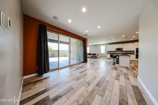 3907 S 75th Dr, Phoenix, AZ 85043 - unfurnished living room featuring a sink, light wood-type flooring, baseboards, visible vents, and recessed lighting