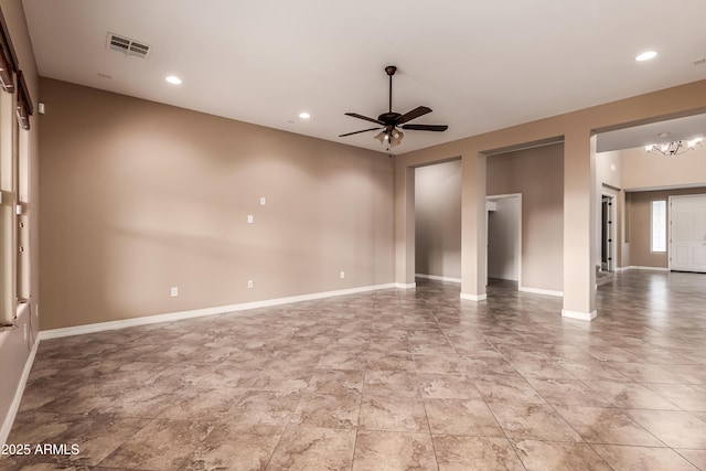 spare room with ceiling fan with notable chandelier