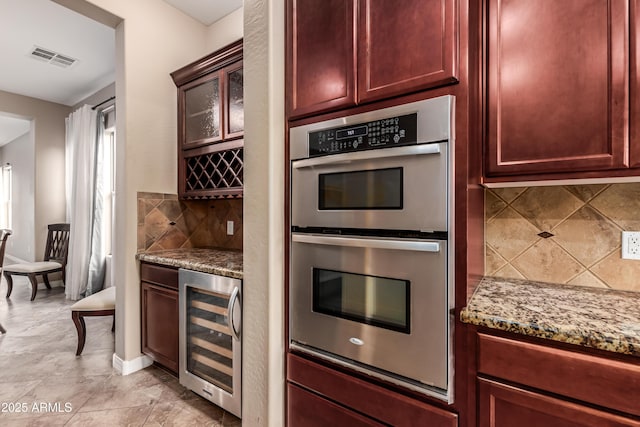 kitchen featuring stainless steel double oven, tasteful backsplash, wine cooler, and light stone counters