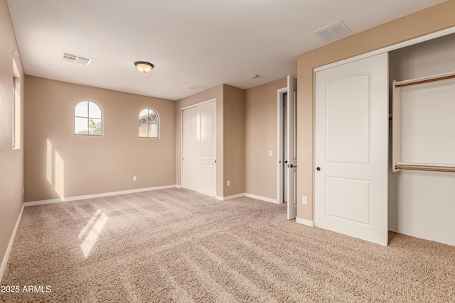 unfurnished bedroom featuring carpet and two closets