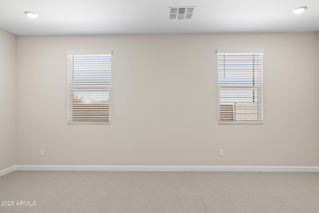 empty room featuring visible vents, light carpet, and baseboards