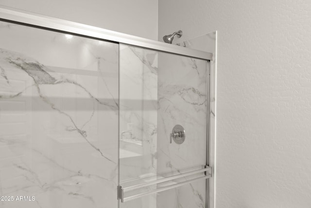 bathroom featuring a textured wall and a marble finish shower