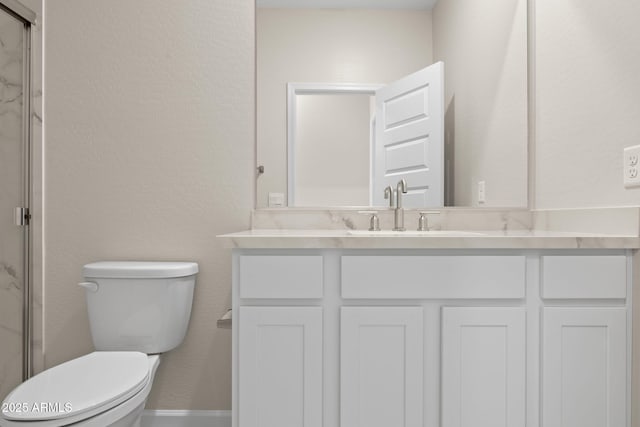 full bath featuring vanity, a marble finish shower, and toilet