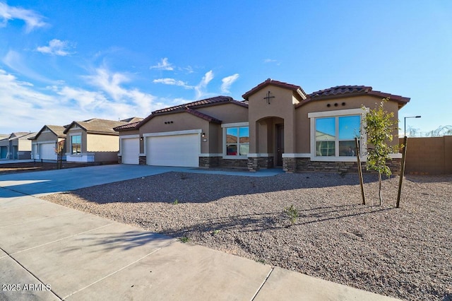 mediterranean / spanish house featuring stucco siding, an attached garage, fence, stone siding, and driveway