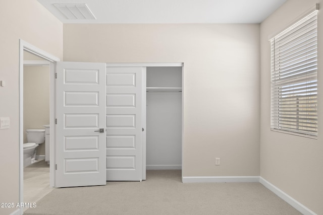 unfurnished bedroom with baseboards, visible vents, a closet, and light colored carpet