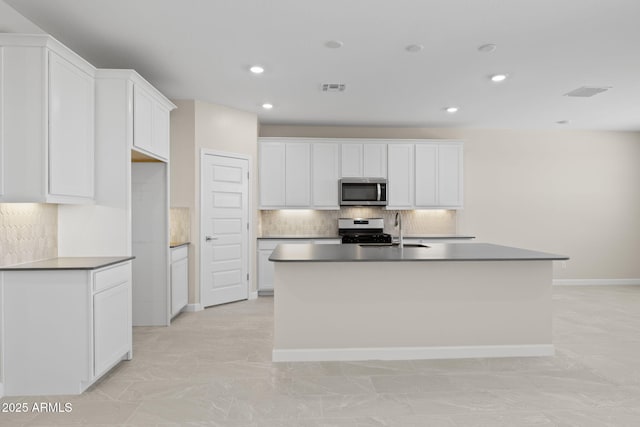 kitchen with a sink, visible vents, appliances with stainless steel finishes, decorative backsplash, and a center island with sink