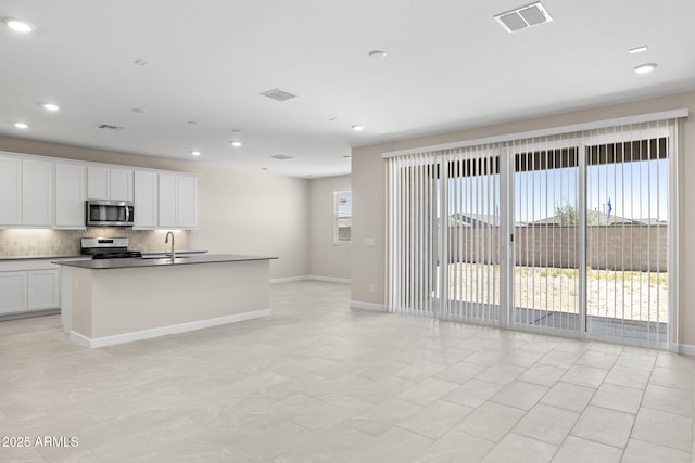 kitchen featuring tasteful backsplash, visible vents, appliances with stainless steel finishes, a sink, and baseboards