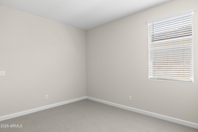 empty room featuring a wealth of natural light, light colored carpet, and baseboards