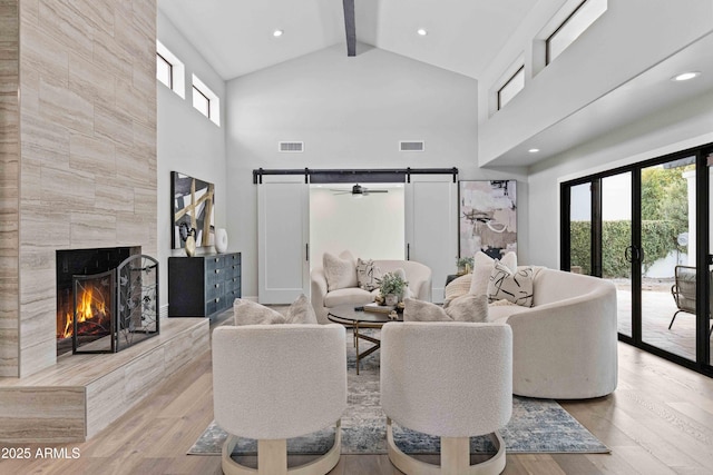 living room with a fireplace, light wood-type flooring, plenty of natural light, and a barn door