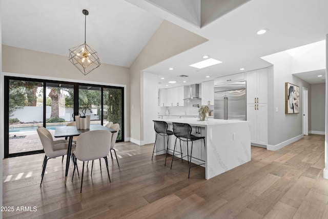 dining area with light hardwood / wood-style floors, a chandelier, and lofted ceiling