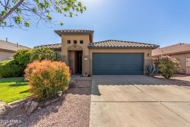 mediterranean / spanish home with a tile roof, stucco siding, an attached garage, and driveway
