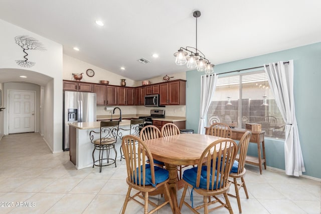 dining area featuring light tile patterned floors, arched walkways, vaulted ceiling, and visible vents