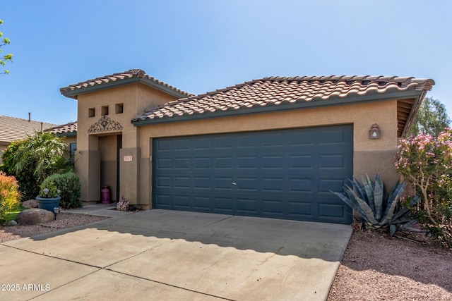 mediterranean / spanish house featuring a tile roof, stucco siding, a garage, and driveway