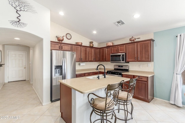 kitchen featuring light countertops, a sink, stainless steel appliances, visible vents, and arched walkways