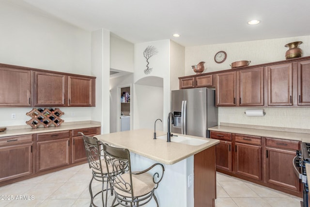 kitchen with light tile patterned flooring, light countertops, stainless steel fridge, and a breakfast bar