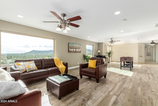 living room with light hardwood / wood-style flooring, ceiling fan, and a mountain view