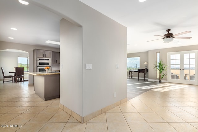 hall with plenty of natural light, french doors, and light tile floors