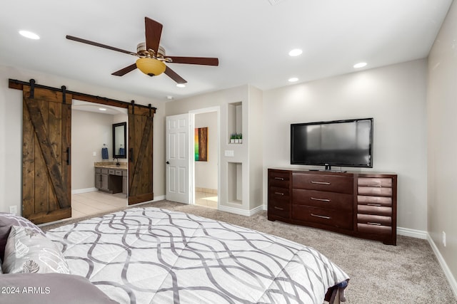 carpeted bedroom featuring sink, ceiling fan, ensuite bath, and a barn door