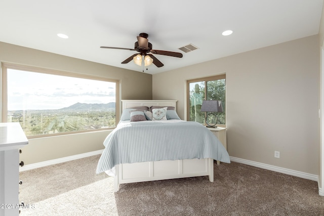 bedroom with a mountain view, ceiling fan, and dark colored carpet