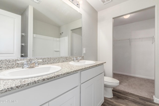 255 W Dewey Ave, Coolidge, AZ 85128 - bathroom with wood finished floors, toilet, a spacious closet, double vanity, and a shower