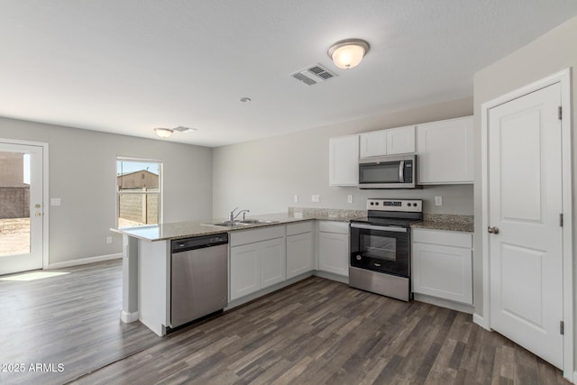 255 W Dewey Ave, Coolidge, AZ 85128 - kitchen with appliances with stainless steel finishes, a peninsula, a sink, dark wood-style floors, and white cabinetry