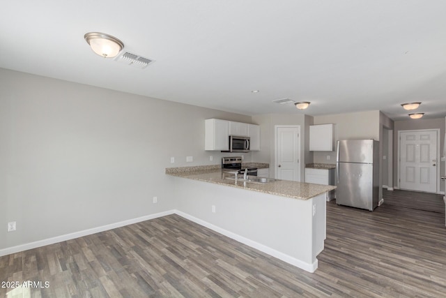 255 W Dewey Ave, Coolidge, AZ 85128 - kitchen with appliances with stainless steel finishes, baseboards, dark wood-style floors, white cabinetry, and a peninsula