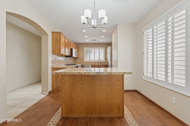 4718 E Woburn Ln, Cave Creek, AZ 85331 - kitchen featuring appliances with stainless steel finishes, light wood-style flooring, a chandelier, arched walkways, and recessed lighting