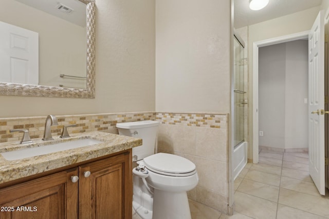 4718 E Woburn Ln, Cave Creek, AZ 85331 - full bath with toilet, vanity, tile patterned flooring, tile walls, and bath / shower combo with glass door