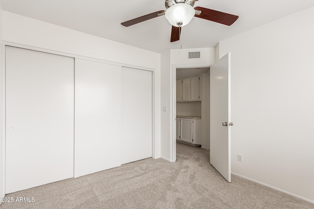 unfurnished bedroom featuring ceiling fan, a closet, and light carpet