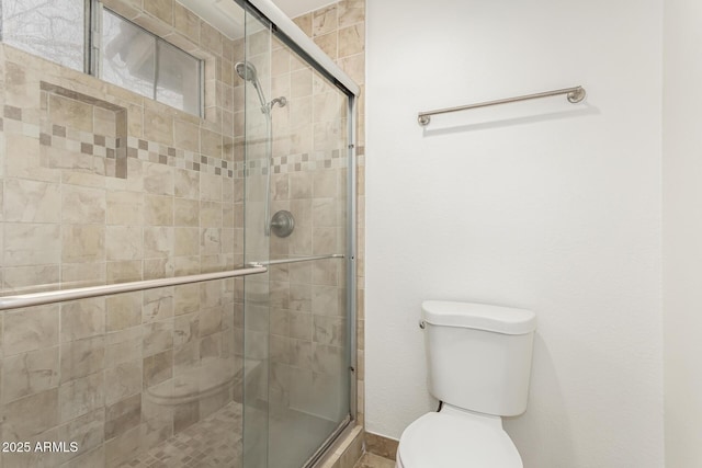 bathroom with toilet and a shower with door