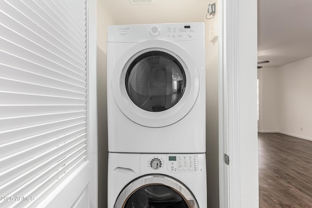 laundry room with stacked washer / drying machine and dark hardwood / wood-style floors