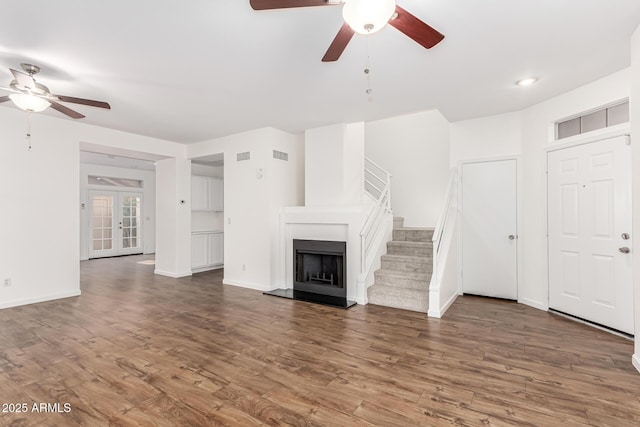 unfurnished living room with dark wood-type flooring, ceiling fan, and french doors