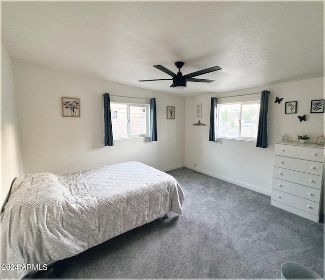 bedroom with ceiling fan, multiple windows, a textured ceiling, and carpet