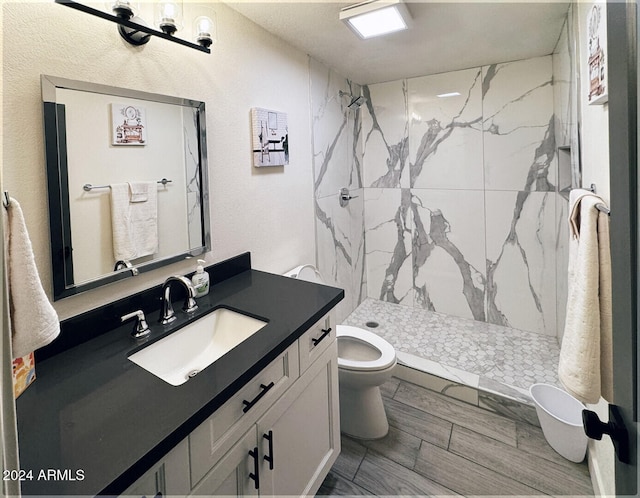 bathroom featuring vanity, toilet, and tiled shower