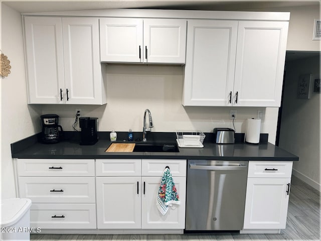 kitchen with dishwasher, white cabinetry, sink, and light hardwood / wood-style flooring