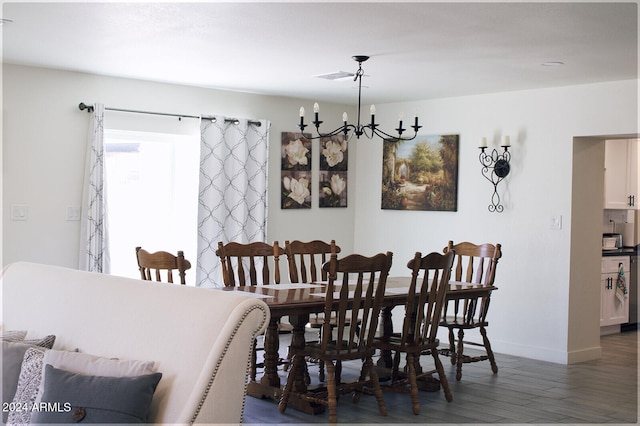 dining area featuring dark wood-type flooring and an inviting chandelier