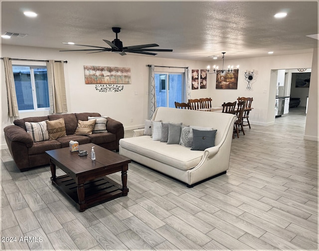 living room with a textured ceiling, ceiling fan with notable chandelier, and light hardwood / wood-style flooring