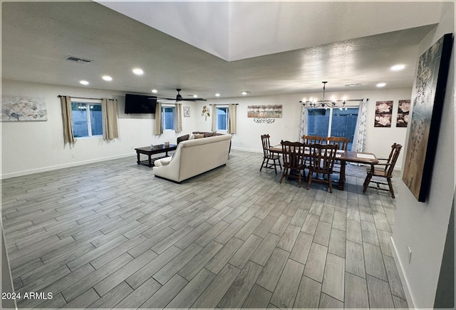 living room with hardwood / wood-style floors and ceiling fan with notable chandelier